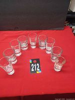 Nine of the shot glasses arranged in semicircle on red cloth