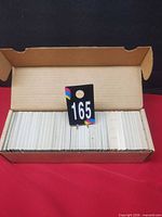 Closed cardboard card storage box holding unsorted cards, lot tag visible