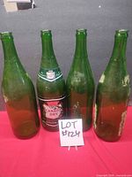 Four green Canada Dry bottles, one with label, lot tag visible