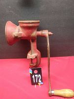 Full view of red cast iron grinder with clamp and crank