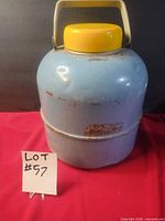 front view of blue JC Higgens water jug showing yellow cap, cream handle, rust spots