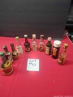 Group shot of all ten empty vintage miniature liquor bottles arranged on red surface