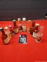 Group shot of all ten vintage mini liquor bottles on red surface