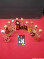 Group shot of ten empty mini liquor bottles arranged in a semi-circle on red surface