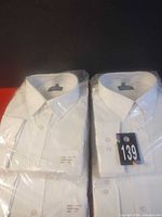 Four packaged white dress shirts with collars visible