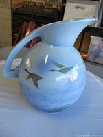 Front view of round blue Falcon Ware pitcher with flying ducks design.