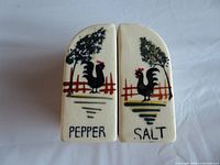 Front view of both ceramic shakers showing rooster artwork and labels