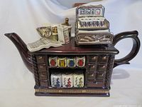 Full view of Paul Cardew Tea Shop teapot, spout, handle, register, canisters visible