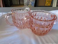 Front view of pink depression glass sugar bowl and creamer showing overall design and condition
