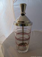 Front view showing glass with measuring bands, metal lid and knob