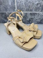 side view of sandals showing woven upper, ruffle toe strap, ankle strap, block heel