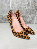 Side view of both pumps showing leopard print uppers and pointed toes