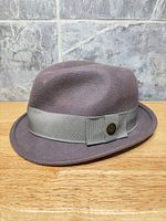 Side view of mauve felt fedora with ribbon and logo button