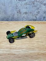 Side view showing green body, yellow fins, number 06, exposed engine