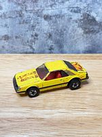 Left side and rear three-quarter view showing yellow body, red interior, flame graphics, wheel type