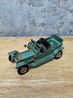 Front-left view of the metallic green Rolls-Royce model showing body, wheels, brass-tone front details