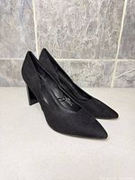 Left side view of both black pointed-toe booties showing heel and upper material