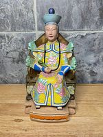 Front view of painted seated Chinese official statue on throne