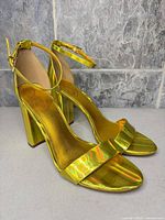 Side angle of both sandals showing iridescent finish, block heels, front straps, ankle straps