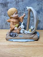 Front view of figurine showing child, rabbit, cat in crescent boat