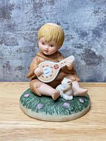 Front view of figurine showing child, instrument, rabbit and base details