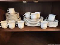 Stacks of plates with multiple cups on shelving