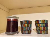 Front view of Archipelago candle beside two mosaic votive holders
