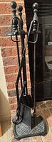 Full view of cast iron fireplace tool set on stand