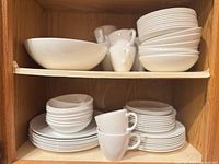 Open cupboard showing stacks of plates, bowls and cups