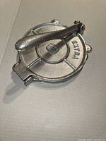 Full view of silver cast metal tortilla press with lever handle, closed position