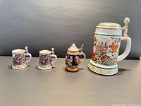 Front view of all four steins showing relative sizes and decoration