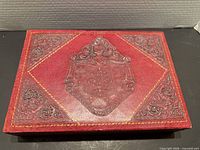 Closed valet box showing embossed crest and scroll corners