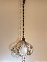 Full view of pendant light hanging from chain against wall