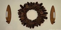 Front view of both sconces and pinecone wreath mounted on wall