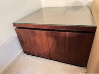 Front left view of square veneer end table with glass top against wall