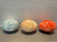 Three polished stone eggs side by side showing color range and finish