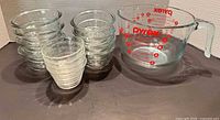 Pyrex measuring cup and 12 glass ramekins side by side