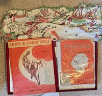 Lot overview showing booklet, two sheet music pieces in sleeves, and printed scarf laid out