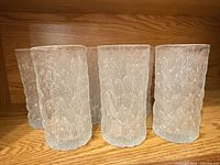 Front view of six textured glass tumblers on shelf