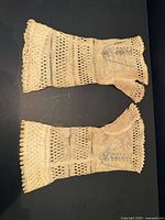Both wristlets laid flat showing openwork knit and overall discoloration
