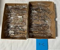 Two cardboard trays containing multiple individually bagged eyeglass frames