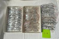 Three boxes of bagged metal eyeglass frames showing silver and gold colours