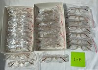 Overall view of three trays filled with individually wrapped gold-tone eyeglass frames