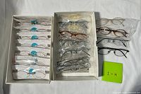 Overview of two boxes and three loose eyeglasses, total ~20 pairs