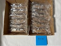Two cardboard boxes containing multiple individually bagged eyeglass frames