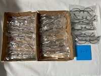 Overall view of two boxes and additional stack showing all sealed eyeglass frames