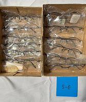 Top view showing both boxes with 12 sealed eyeglass frames and note card