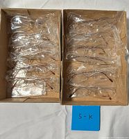 Two cardboard boxes containing sixteen individually bagged metal eyeglass frames