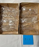 Two cardboard trays holding multiple plastic-wrapped eyeglasses