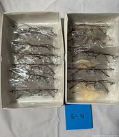 Two boxes showing all twelve packaged eyeglass frames